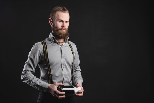 Handsome young man presents car parts on a gray background. The concept of sales and testing of goods