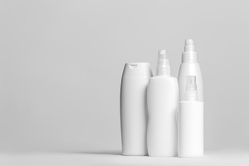 Set of cosmetic products in white and grey containers on light background.