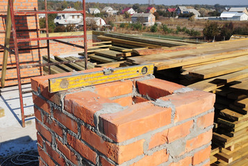 Obraz premium Building a chimney out of masonry, noncombustible red bricks and cement on the rooftop of a house.