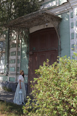 Look of russian girl in beautiful retro dress, vintage hat and porch door of old house in Astrakhan...