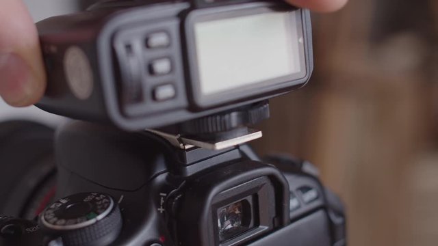 Close-up of the synchronizer attachment to the camera. Connecting the synchronizer to the camera's hot Shoe. A man's hand attaches and secures the synchro for the flash on the camera