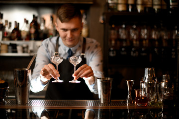 bartender holds in his hands two glasses with ice