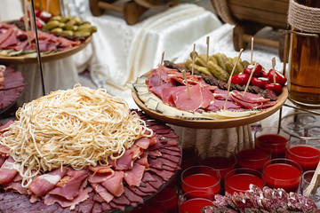 Сheese, cold meats, sliced sausages, cucumbers, tomatoes and fresh red juice on a festive table. Variety of tasty delicious snacks. Food concept