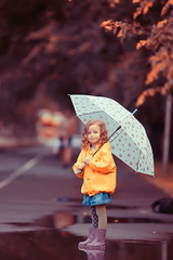little girl with an umbrella / small child, rainy autumn walk, wet weather child with an umbrella