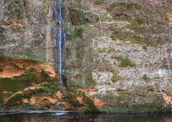 Sandstone rock wall at river with waterfall , rock wall in the Gauja national park, Latvia. River Brasla - 332881910