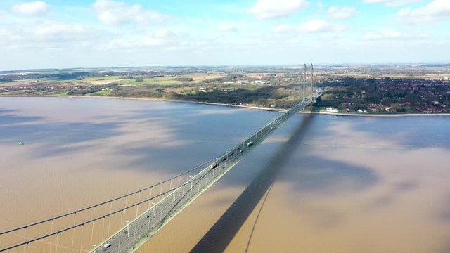 Aerial footage of The Humber Bridge, near Kingston upon Hull, East Riding of Yorkshire, England, single-span road suspension bridge, taken on a sunny day with a few white clouds in the sky.
