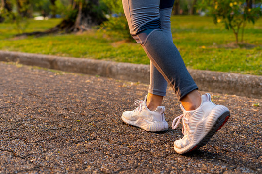 Young woman walking exercise on a brown street with white shoes exercising
