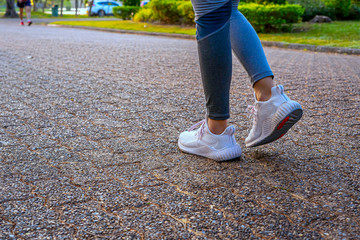 Young woman walking exercise on a brown street with white shoes exercising