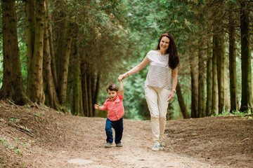 Mother having fun with cute son in summer park. Happy woman with cheerful little boy outdoors