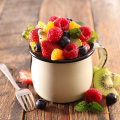 mixed fruit salad in mug with berry fruit, orange, banana and orange