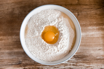 Plate with flour and egg on top for making dough on a sunny day.