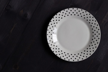white plate  with polka dot pattern  on black background
