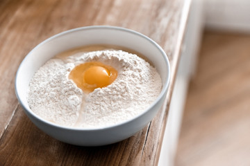 Plate with flour and egg on top for making dough on a sunny day.