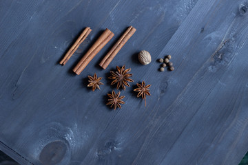 Star anise, cinnamon sticks, nutmeg, allspice  on black wooden background