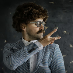 mustachioed man in a classic suit and vintage glasses, curly hipster portrait, long hair