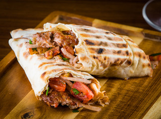 Shawarma pita bread with grilled chicken, shaurma doner, fresh vegetables and cream sauce on a light stone or concrete background. Top view with copy space, concept restaurant fast food