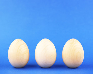 wooden eggs on a blue background. three eggs in a row. background for the religious holiday of Easter