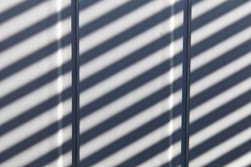 Vertical white plastic planks with diagonal sun rays blsck shadows, texture for background
