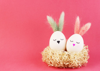 Easter eggs rabbits on a pink background. eggs with cute faces and pink ears. Rabbit girl and rabbit boy in the nest. a nest of decorative paper