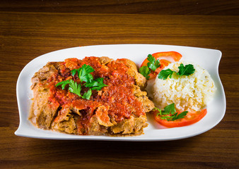 Traditional Turkish iskender kebap doner served with special red sauce and yogurt in the middle garnished with grilled tomatoes and peppers chicken