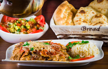 Traditional Turkish iskender kebap doner served with special red sauce and yogurt in the middle garnished with grilled tomatoes and peppers chicken
