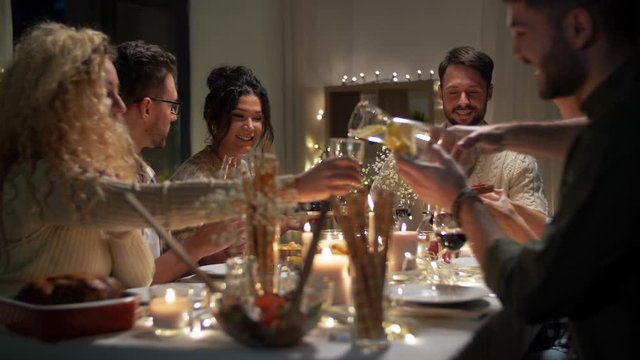 holidays, food and people concept - happy smiling friends having christmas dinner and eating at home in evening