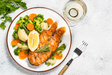 Grilled salmon fish steak with vegetables on white.