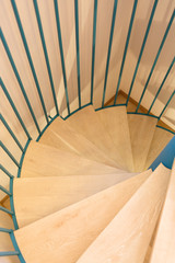 Spiral staircase, forged green handrail and wooden steps in modern home.