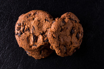 Appetizing chocolate chip cookies with slices of raisins on a black background.