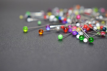 A lot of colored sewing pins on a black background.