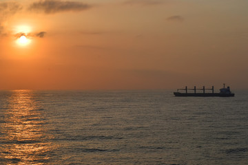 Obraz na płótnie Canvas cargo ship on the ocean at sunset for logistics international transport