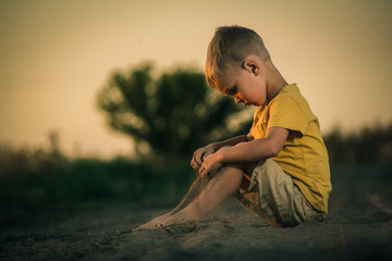 Obraz premium little boy plays in the dust at sunset