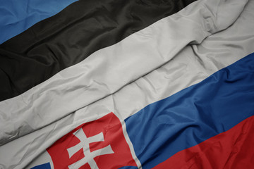 waving colorful flag of slovakia and national flag of estonia.