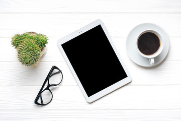 Flat lay home office workspace. Tablet, glasses, cup of coffee, succulent on white wooden background. Top view Business, freelance work concept