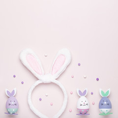 Funny kawaii cute bunny eggs and bunny rabbit ears for kids in pastel colors on pink table top, Easter holiday concept. Easter decoration for kids still life, copy space