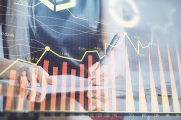 A woman hands writing information about stock market in notepad. Forex chart holograms in front. Concept of research.