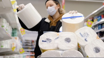Woman Buying Toilet Paper During Coronavirus Outbreak or Covid-19 In Supermarket. Concept of Covid-19 Quarantine.