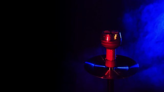shisha bowl of the hookah with hot coals against a dark background