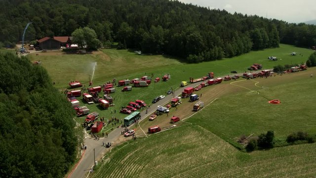 helicopter flight along forest fire drill with a lot of fire engines and fire fighters