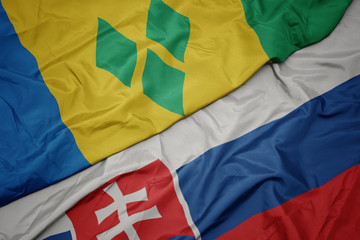 waving colorful flag of slovakia and national flag of saint vincent and the grenadines.