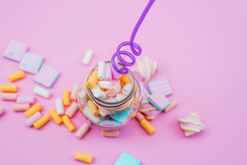 Colorful marshmallows in a glass on pink background. Party concept.