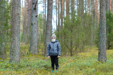 Disappointed lonely kid wearing mask for protection of corona virus spread on a empty forest.