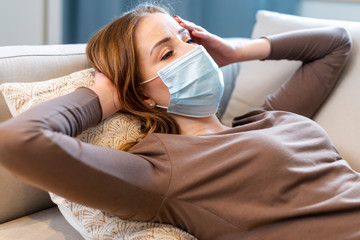 Medium shot woman with mask staying on the couch