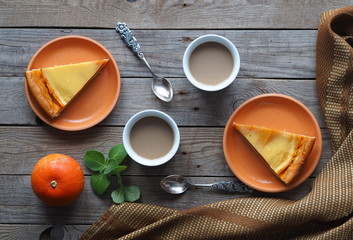 Homemade pumpkin pie covered in whipped eggs with cream and sugar, and a Cup of coffee on a wooden rustic background.Close up.