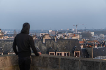 Silhouette of a man looking at a gorgeous cityscape from the castle of Caen with a thick haze over the city