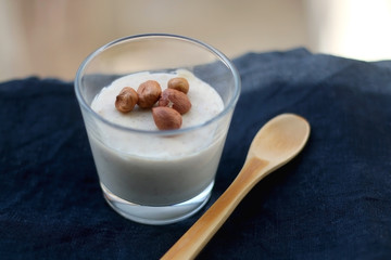 Glass of vanilla pudding with hazelnut topping and wooden spoon. Selective focus.
