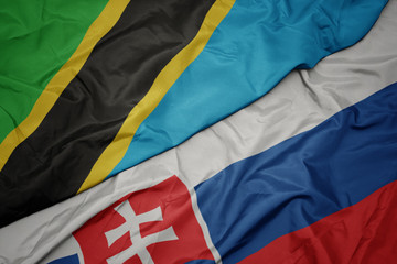 waving colorful flag of slovakia and national flag of tanzania.