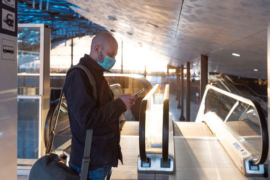 Man In Mask While Coronavirus And Pandemic Stay Safety In Public Transport At The Airport.  Business During The Danger Of Covid19 In The City At Sunset. Face Mask And Health Care Among People.