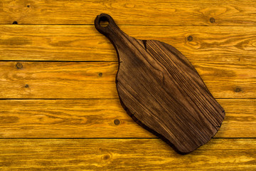 Cutting board lies on a light brown wooden background.