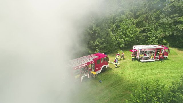 firefighters with their fireengine in the smoke close to a forest fire